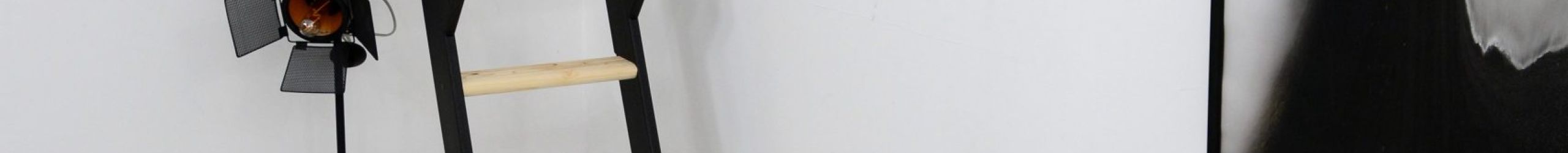 Space-saving staircase Strong with a black frame and spruce treads. The staircase is steeply mounted to the wall and features a black wooden handrail on both sides.