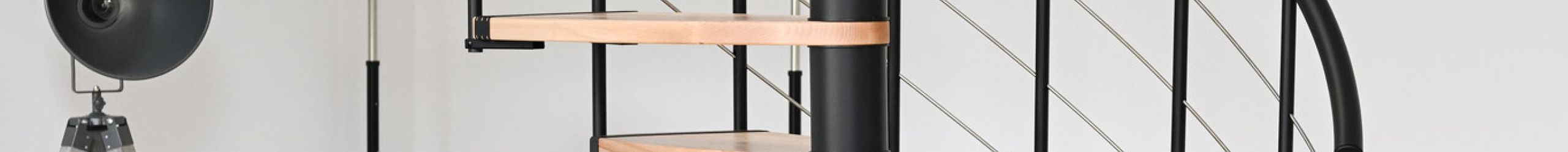 Helios spiral staircase in a modern living space. The elegant combination of light wooden steps and black metal creates a stylish and space-saving design. Perfect for open living concepts.