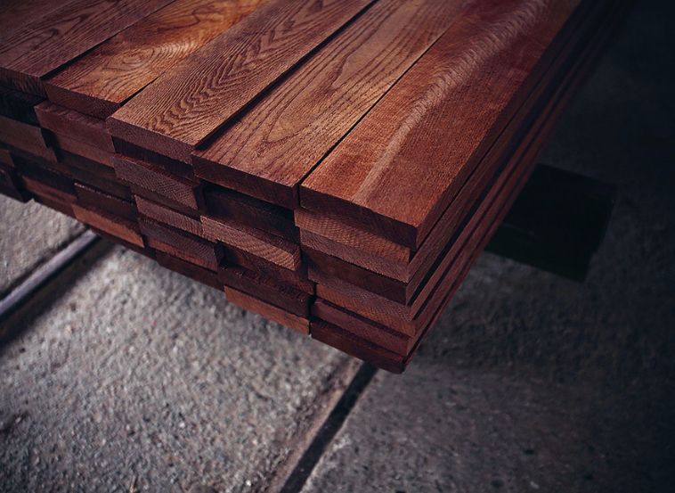 Stack of thermally treated wooden boards with a dark, even color and enhanced durability.