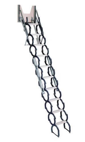 A toddler plays with colorful toys on the floor in front of the mounted "Annika" wooden child safety gate. The gate is installed between two walls, separating the play area from the kitchen behind.