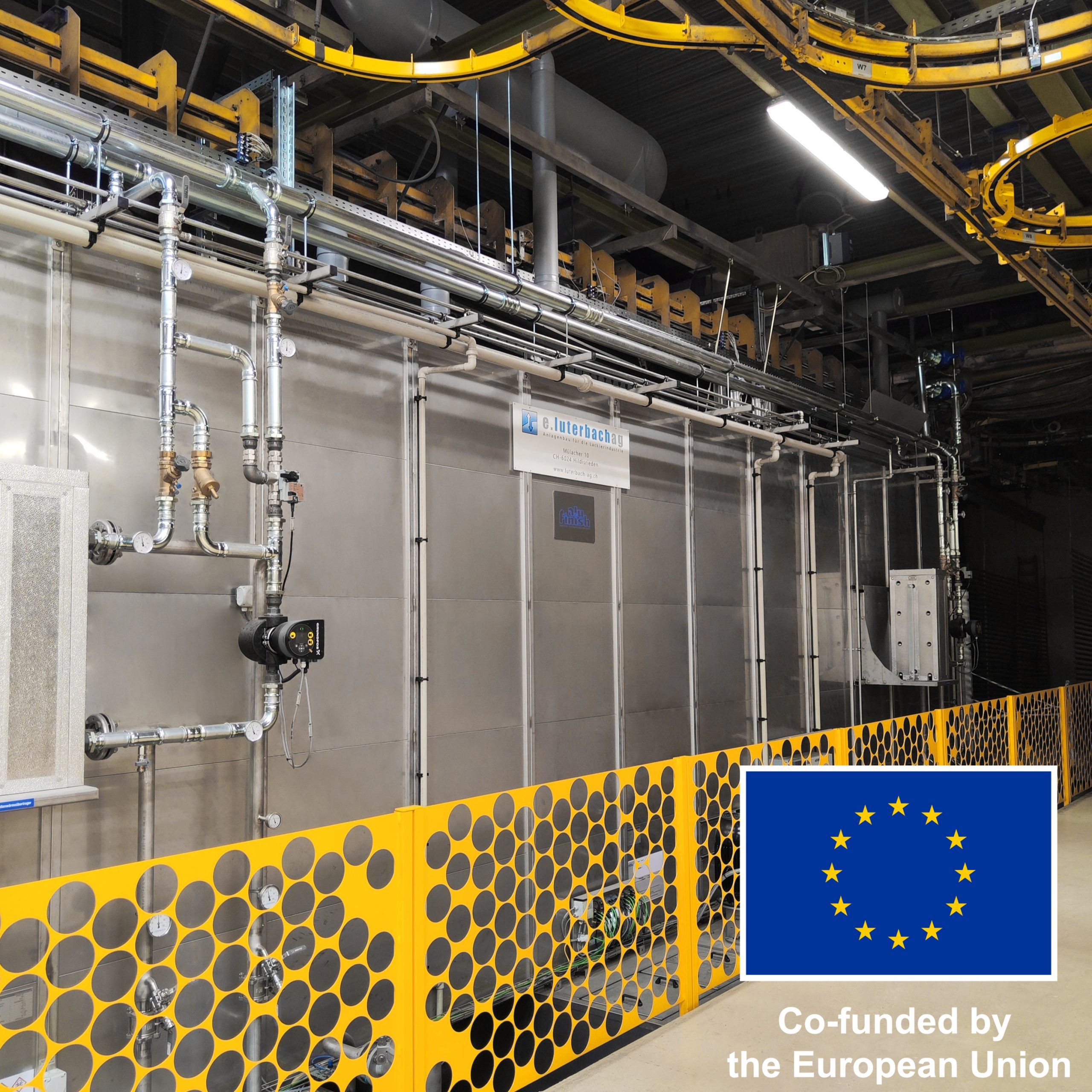 New pre-treatment system at the Minka powder coating facility, co-funded by the European Union, featuring modern piping and safety barriers.