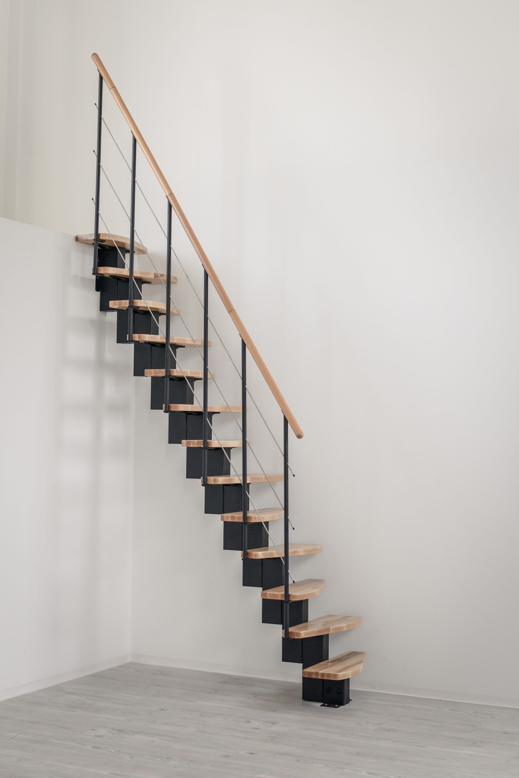 Quatro central stringer staircase with beech steps and a black metal railing with horizontal bars and a wooden handrail.