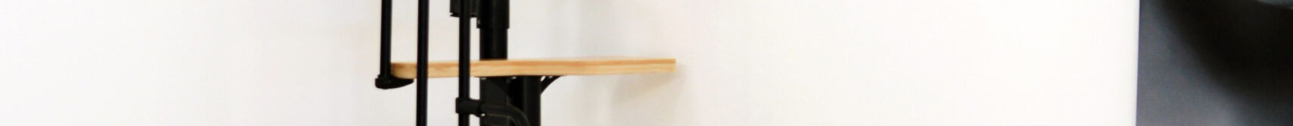 Twister space-saving staircase with alternating beech steps and a black metal structure. Equipped with a side metal railing that curves at the top end.