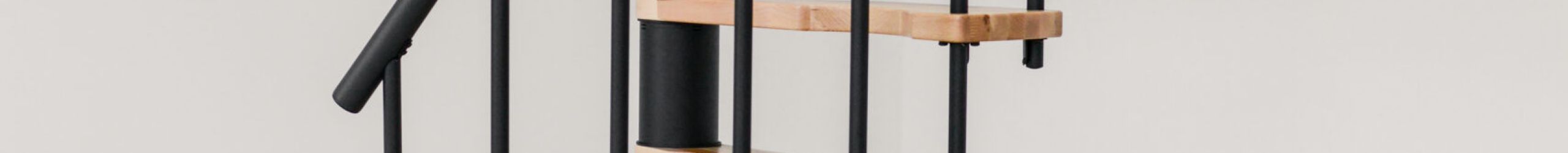 The Suono Smart spiral staircase features a space-saving design with a black central column, black railing rods, and light wooden steps – ideal for minimalist living spaces.