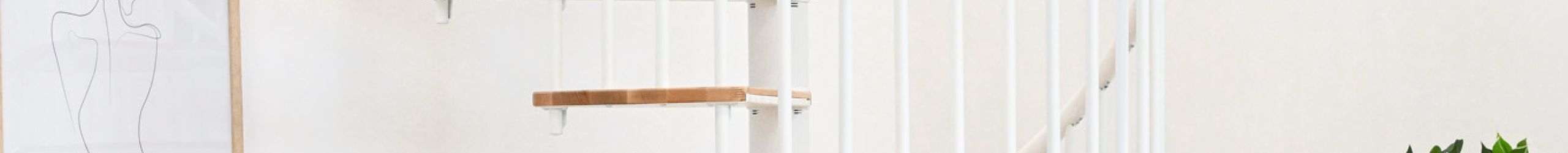 Switch spiral staircase with beech steps and white metal banister installed in a bright room with plants, chair and side table