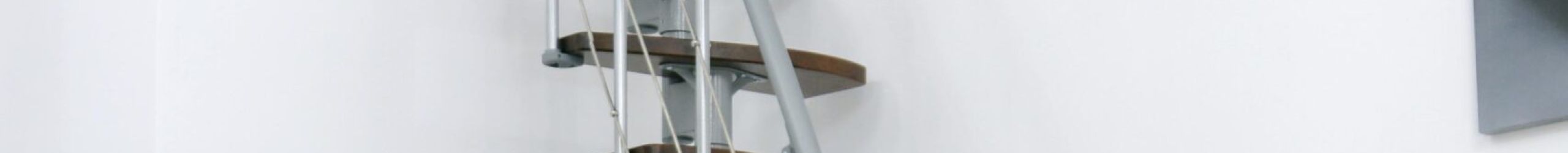 Straight Nizza space-saving staircase with alternating steps in walnut finish and a grey metal structure. The staircase is installed compactly along a white wall and features a side railing with horizontal bars and a grey handrail.