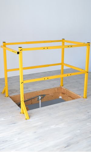 A toddler plays with colorful toys on the floor in front of the mounted "Annika" wooden child safety gate. The gate is installed between two walls, separating the play area from the kitchen behind.