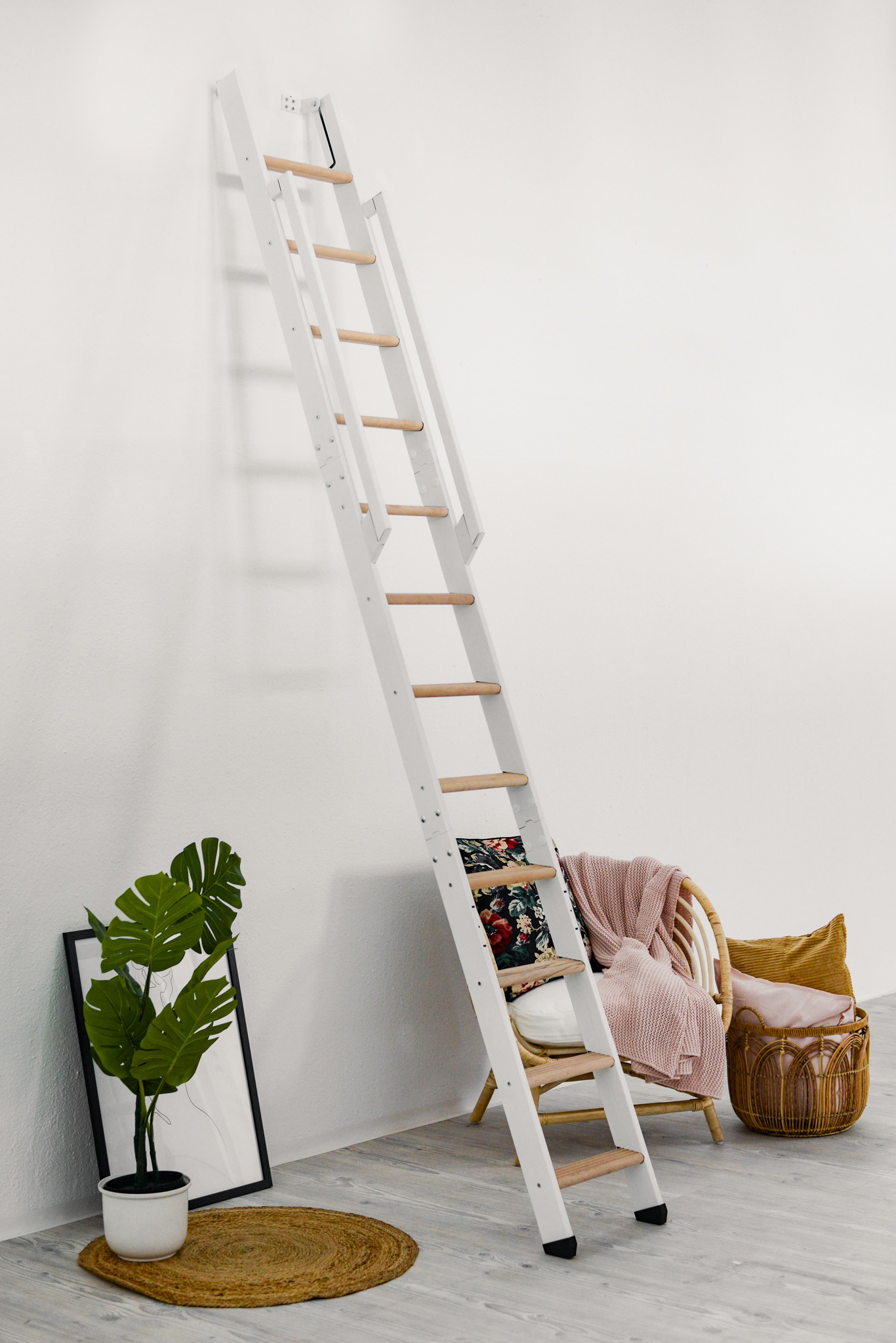 Space-saving staircase Strong with a white frame and beech treads. The staircase is steeply mounted to the wall and features a white wooden handrail on both sides.