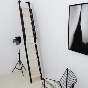 Space-saving staircase Strong with a black frame and spruce treads. The staircase is steeply mounted to the wall and features a black wooden handrail on both sides.