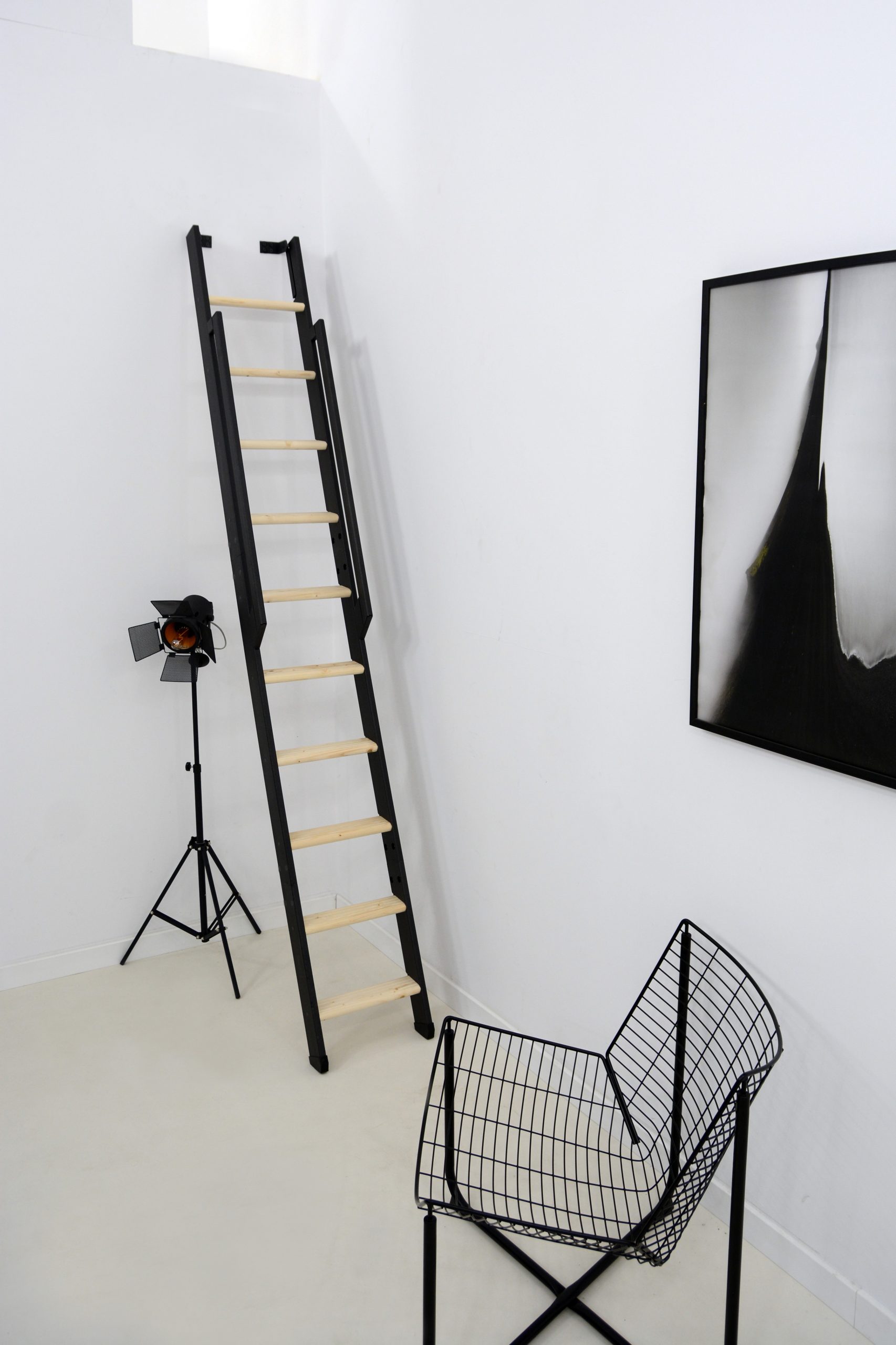 Space-saving staircase Strong with a black frame and spruce treads. The staircase is steeply mounted to the wall and features a black wooden handrail on both sides.