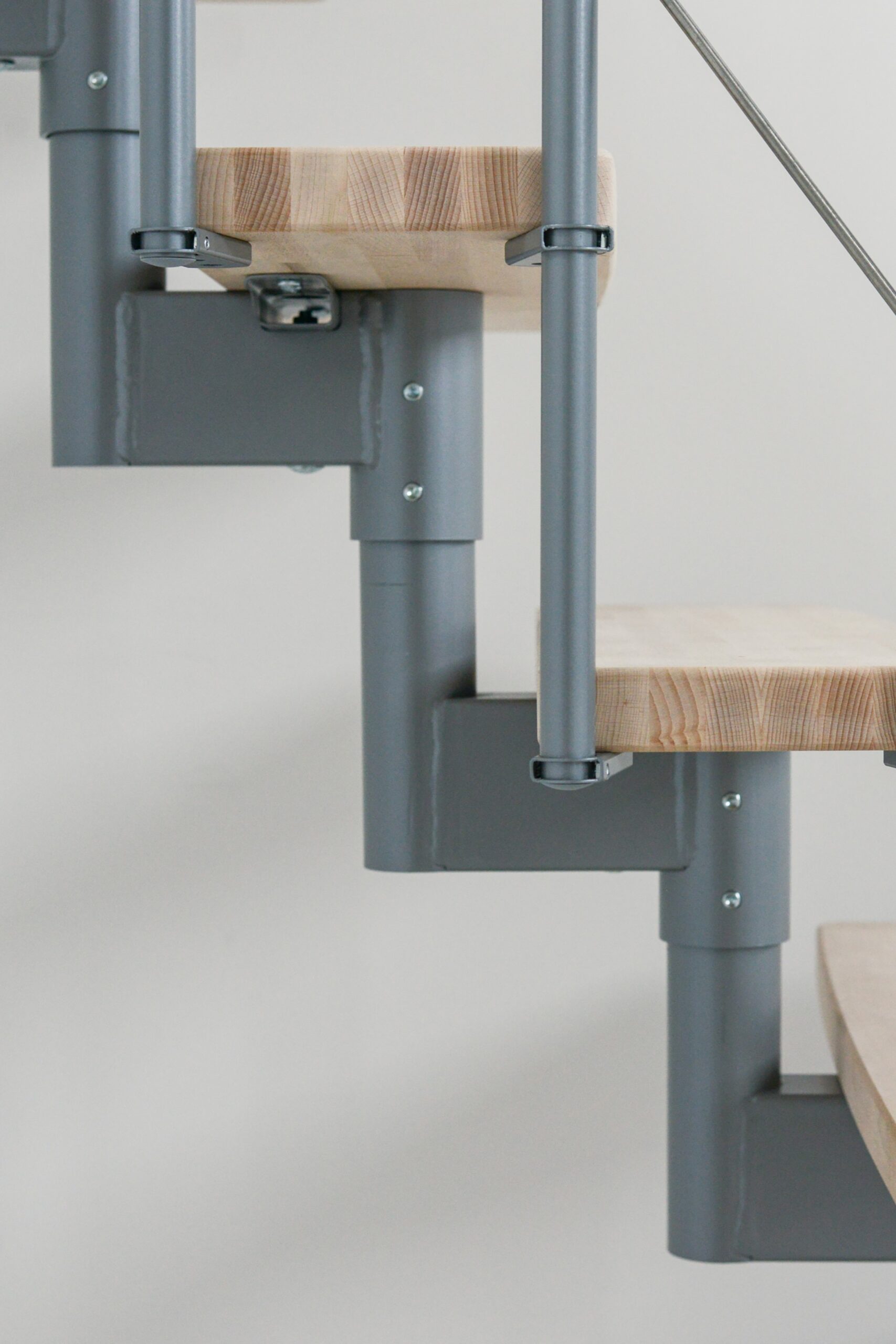 Close-up of the Style Turn staircase with beech wood steps attached to a gray metal structure. The connection between the steps and the metal frame highlights the precise craftsmanship and modern aesthetics.