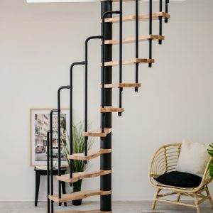 The spiral staircase Suono combines black metal elements with light wooden steps. The space-saving design fits perfectly into modern living spaces and creates a stylish look.