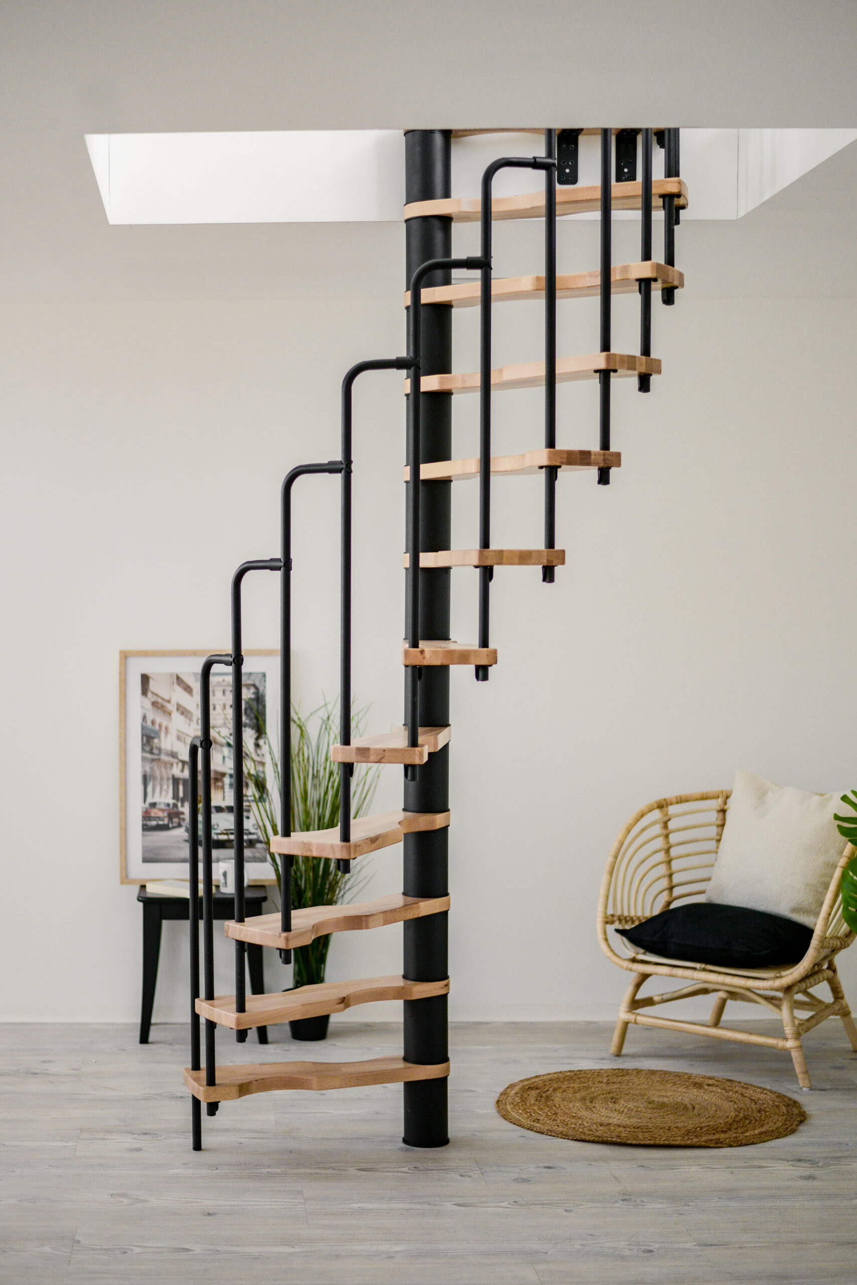 The spiral staircase Suono combines black metal elements with light wooden steps. The space-saving design fits perfectly into modern living spaces and creates a stylish look.