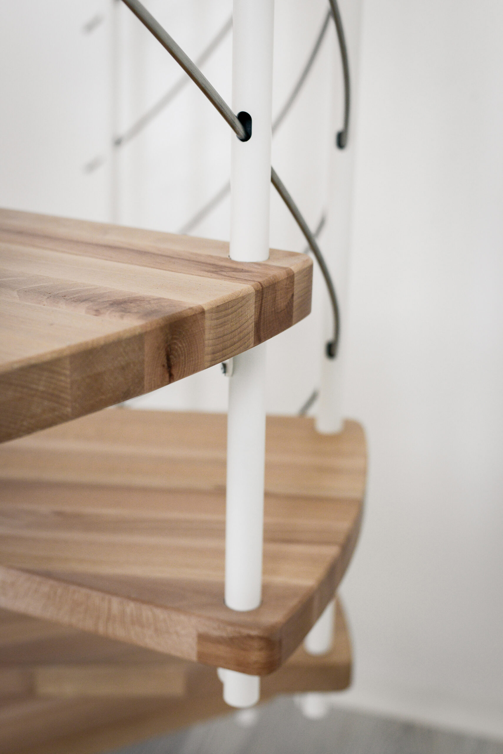 Close-up of the steps of the Venezia Smart spiral staircase made of beech wood with white balusters.