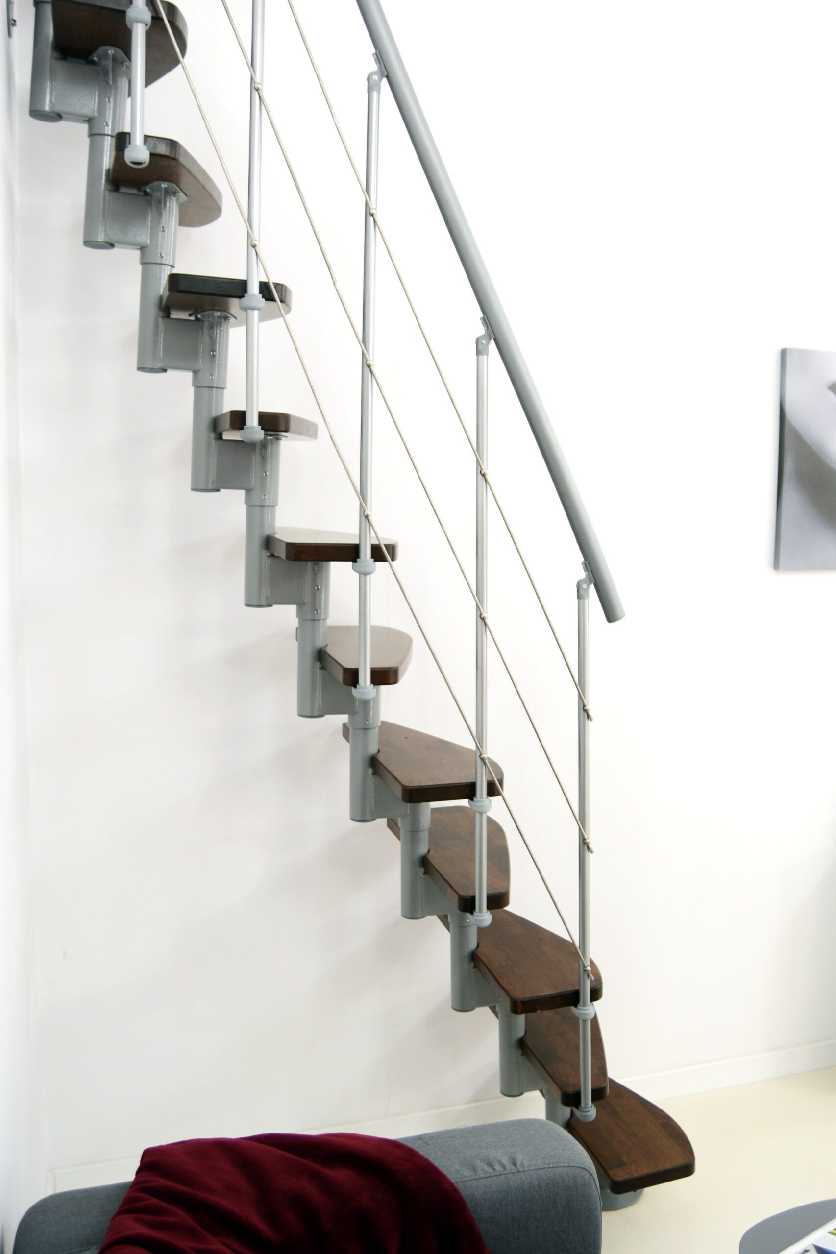 Side view of the Nizza space-saving staircase with alternating steps in walnut finish and grey metal structure.