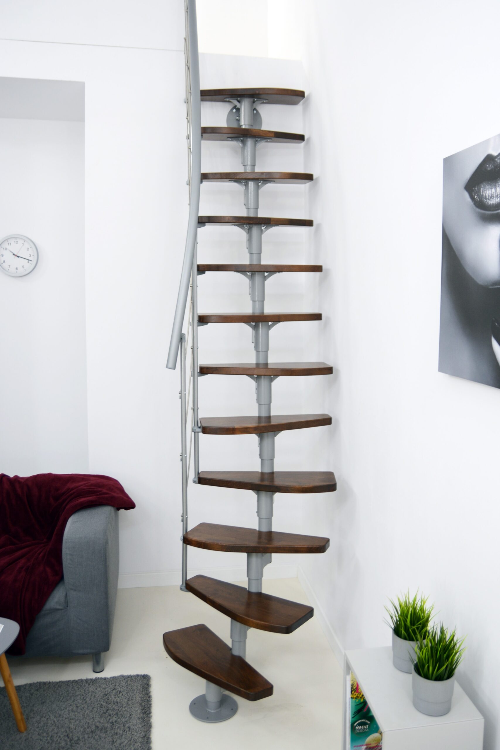 Nizza space-saving staircase with dark brown wooden steps in walnut finish and a grey metal structure. The staircase runs compactly along a white wall.