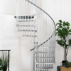 Outdoor spiral staircase Rondo Zink Smart made of galvanized metal in a modern living space. The spiral staircase leads upwards, with plants, a rug and a grey sofa with cushions in the foreground.