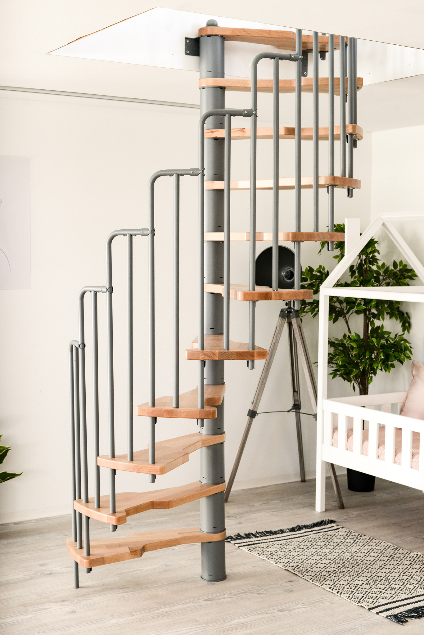 The Metallica spiral staircase combines a grey metal railing with light wooden steps. Perfect for modern living spaces and space-saving solutions, for example in children's rooms.