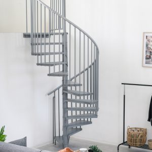 Grey metal spiral staircase Rondo Smart with round steps and vertical railing rods. The space-saving staircase winds upwards in a modern living area with sofa, plants and a clothes rack.