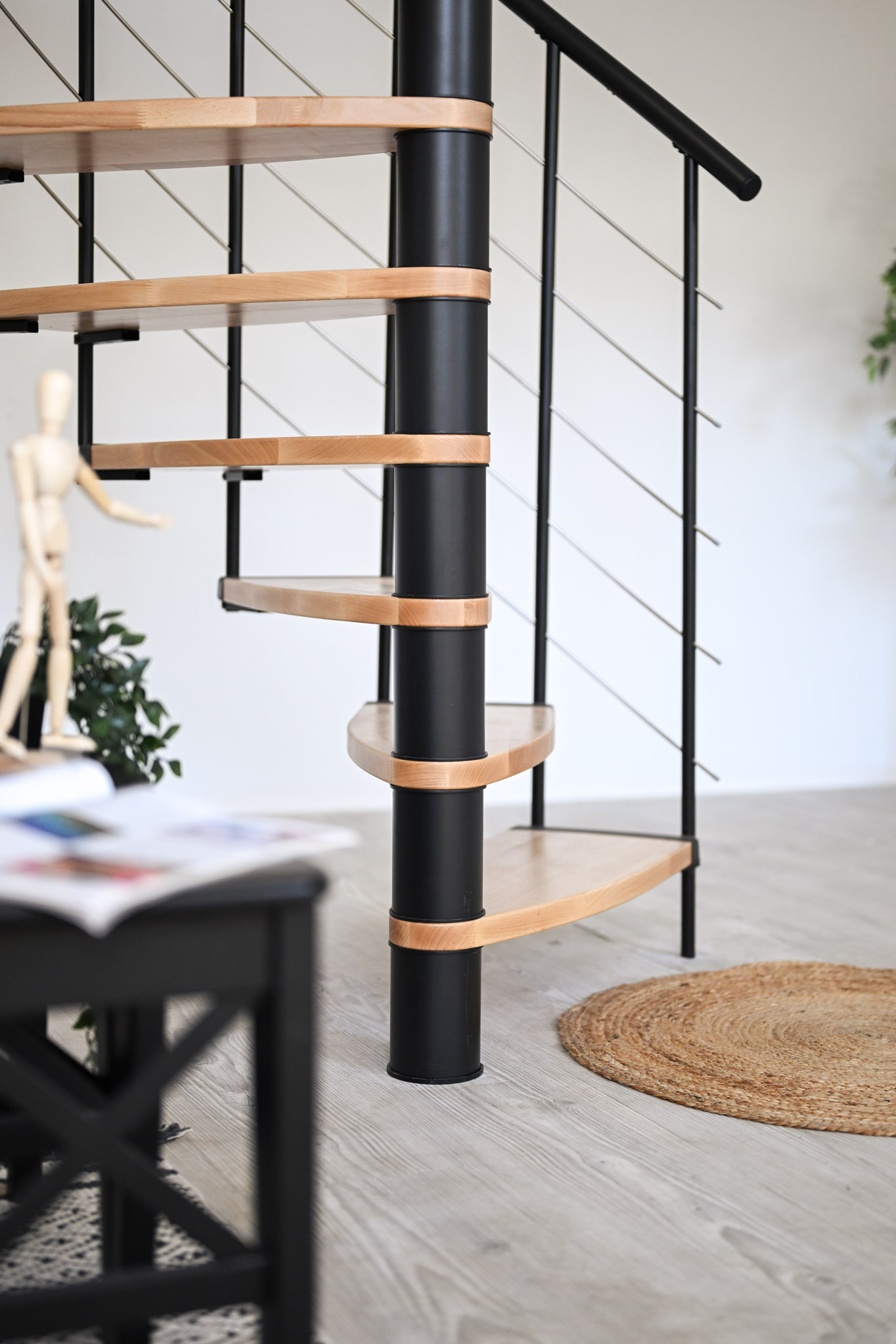 Close-up view of the Helios spiral staircase. The combination of black metal elements and light wooden steps creates a modern and stylish look within the living space.