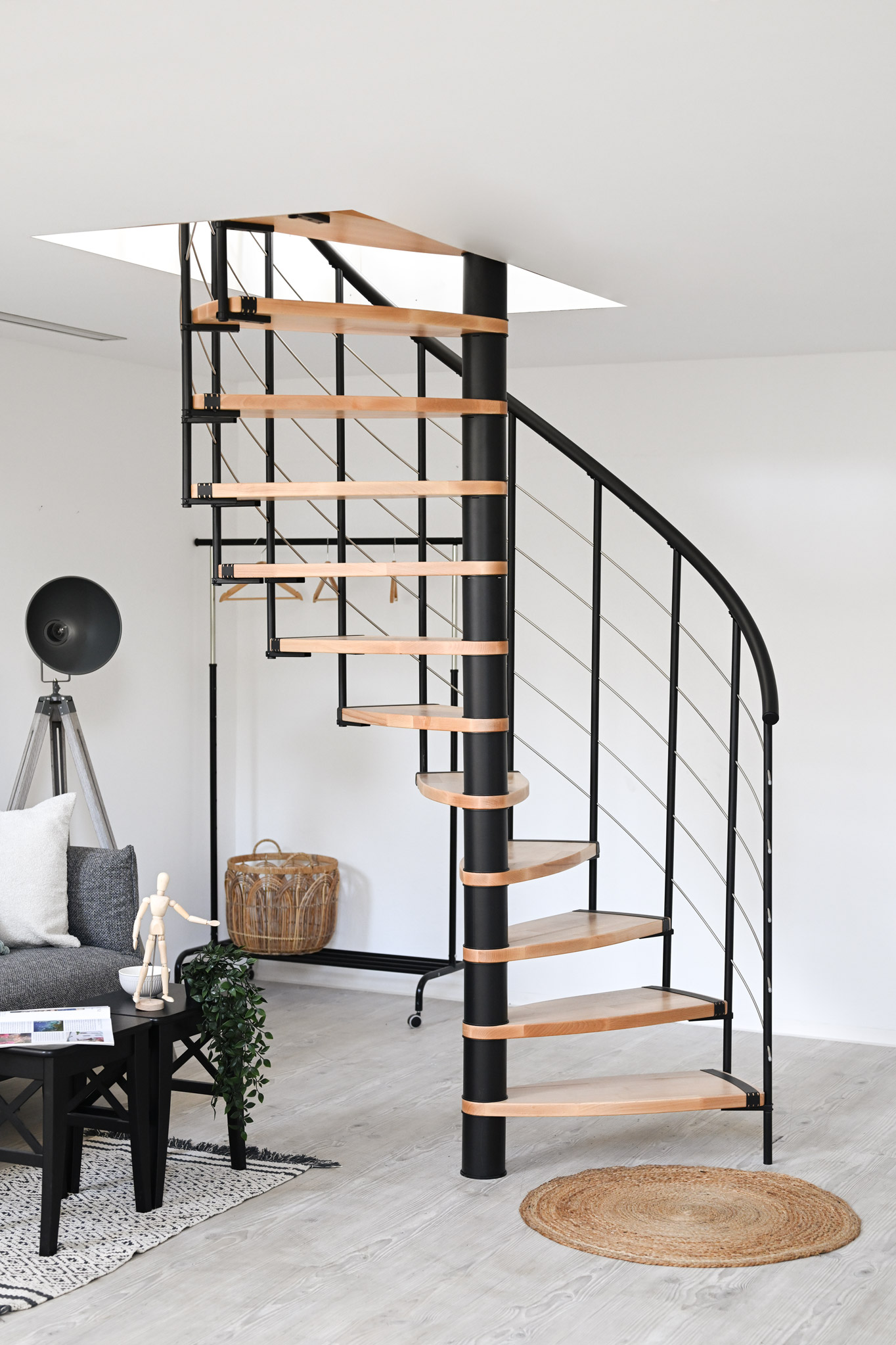 Helios spiral staircase in a modern living space. The elegant combination of light wooden steps and black metal creates a stylish and space-saving design. Perfect for open living concepts.