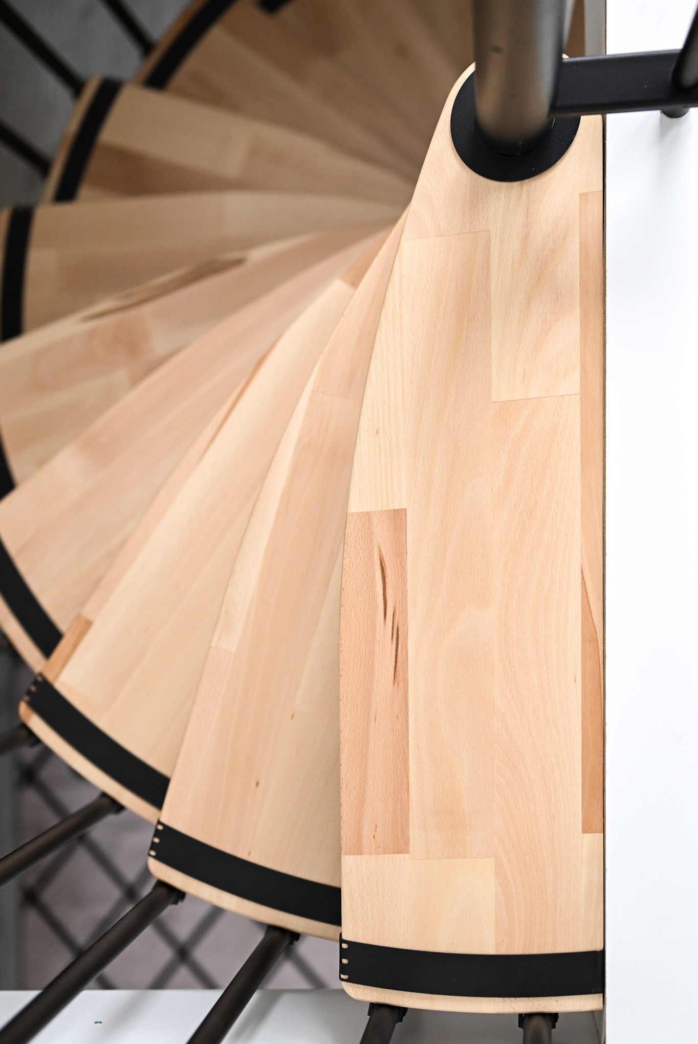 Close-up of the steps of the Luna spiral staircase. The combination of light wood and black accents highlights the modern and high-quality design of the staircase.