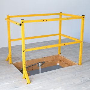 Yellow Minka attic opening safety railing made of metal, rectangular frame for fall protection at ceiling openings, mounted on a light wooden floor.