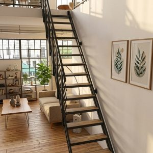 A black metal staircase with wood steps and a banister against a concrete wall in a modern loft with wooden flooring and a large window front.