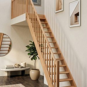 Classic straight staircase in solid beech wood featuring open risers, a traditional vertical spindle balustrade, and a matching handrail, creating a timeless and elegant feature in a bright, contemporary interior.