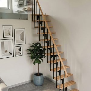 Joker space-saving staircase featuring a black powder-coated steel central support, solid beech wood treads, slim black balustrades, and a matching beech handrail, providing a compact and modern access solution for a gallery level in a contemporary interior.