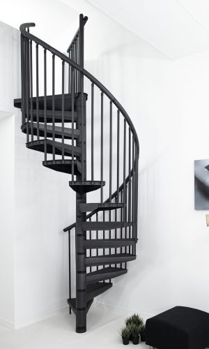 Spiral staircase Rondo Color in anthracite in a bright, modern interior. The steps and vertical bar railing are also in anthracite. The space-saving staircase connects the lower and upper floor and stands against a white wall.