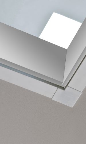 Detail view of a modern white trim strip of the “Minka Fix” type, 18 mm wide, installed around a ceiling opening with a smooth wall junction.