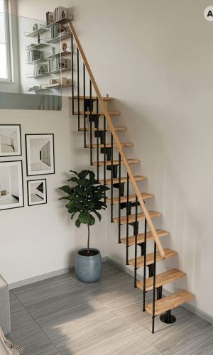Joker space-saving staircase featuring a black powder-coated steel central support, solid beech wood treads, slim black balustrades, and a matching beech handrail, providing a compact and modern access solution for a gallery level in a contemporary interior.