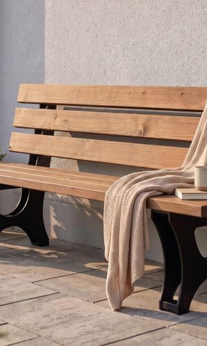 Campo garden bench made of thermally modified pine with a black metal frame on a terrace in front of a house.