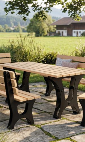 Campo garden dining set with a solid wooden table, two matching benches and one chair featuring black powder-coated steel frames, placed on a stone patio beneath a large tree with a scenic countryside and mountain landscape in the background.