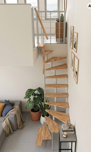 Joker 180° turn spiral staircase featuring a white steel central column, solid beech wood treads, and a matching beech handrail, providing a compact and elegant solution for accessing an upper floor in a bright, modern interior.