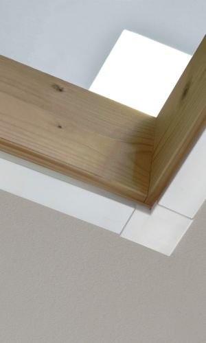 Close-up of a wooden frame with a white trim strip of the type “Minka Fix” measuring 27 mm in width, installed on the ceiling of an interior space.