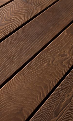 Detailaufnahme der Holzterrassendielen Lotus, gebürstet, schräg verlegt. Die dunkle Maserung und feine Struktur unterstreichen die edle Optik des Minka Wood Lotus-Holzes.