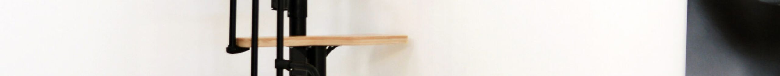 Raumspartreppe Twister mit abwechselnd geformten Buche-Stufen und schwarzer Metallkonstruktion. Ausgestattet mit einem seitlichen Metallgeländer, das am oberen Ende gebogen verläuft.