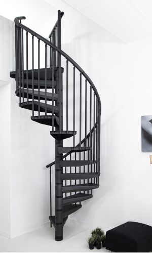 Spindeltreppe Rondo Color in Anthrazit in einem hellen, modernen Innenraum. Stufen und senkrechtes Stabgeländer sind ebenfalls in Anthrazit. Die platzsparende Treppe verbindet das untere mit dem oberen Stockwerk und steht vor einer weißen Wand.