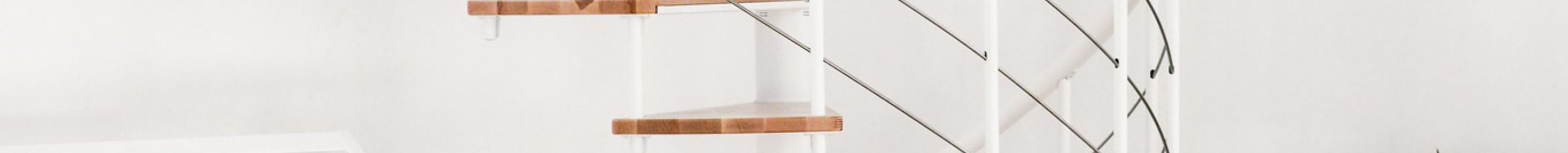 Spindeltreppe Fusion mit Buchenstufen und weißem Metallgeländer eingebaut in einem hellen Raum mit Pfanzen, Kinderbett und Stuhl.