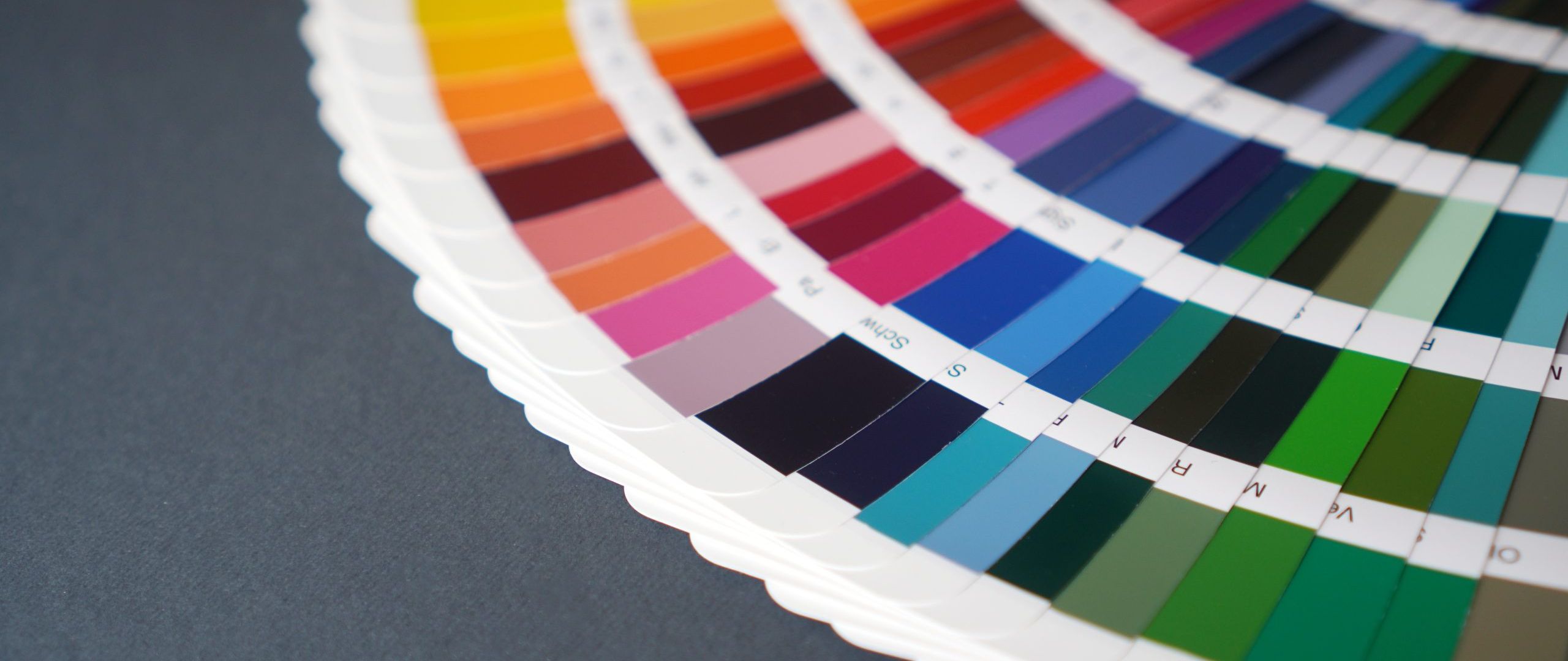 Farbpalette liegt aufgefächert auf einer grauen Tischplatte.