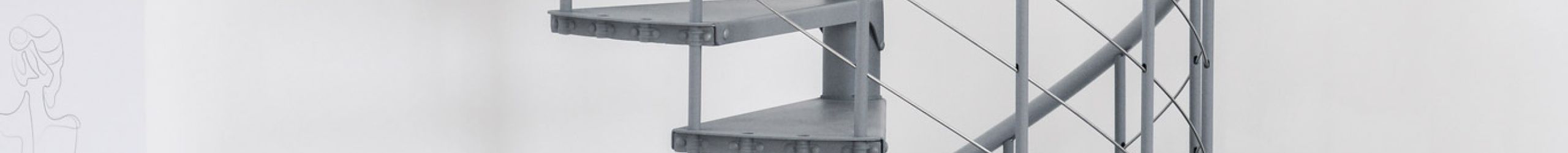 Spindeltreppe Spino Smart in Grau aus Metall im modernen Wohnraum. Die gewendelte Treppe führt nach oben, das Geländer besteht aus senkrechten Streben und Edelstahlseilen. Im Hintergrund stehen ein Sofa, Pflanzen und Deko.