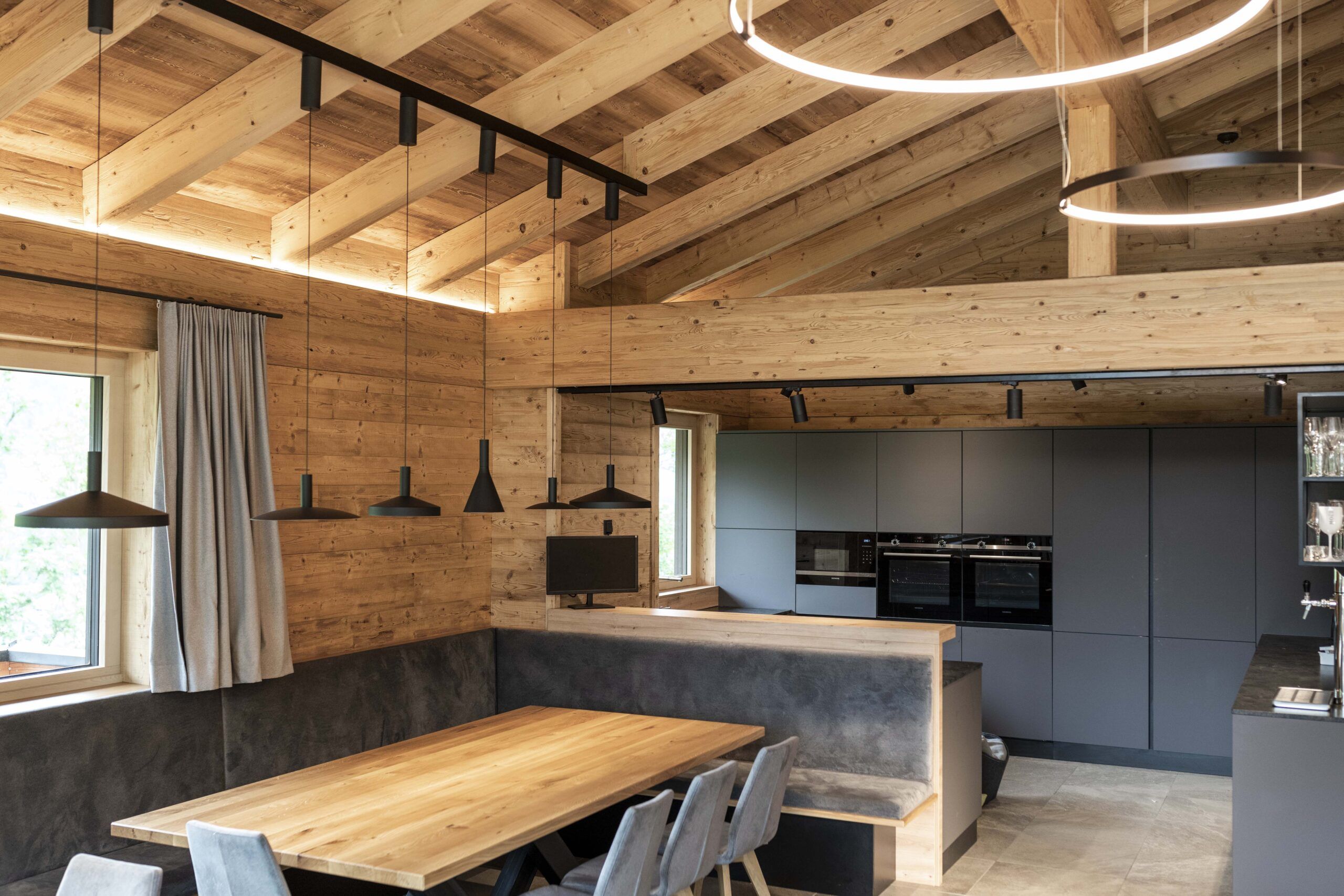 Modernes Badezimmer mit Naturstein-Badewanne, Glasdusche und Waschtisch. Wände und Decke sind mit gebürsteten Gladiola-Holzpaneelen versehen, was eine warme, edle Atmosphäre im Almwelt Schwab-Walcher schafft.