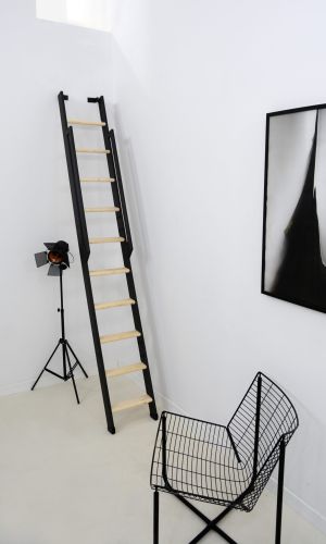 Raumspartreppe Strong mit schwarzem Metallgestell und Trittstufen aus Fichte. Die Treppe ist steil an der Wand montiert und verfügt über ein beidseitiges, schwarzes Metallgeländer.