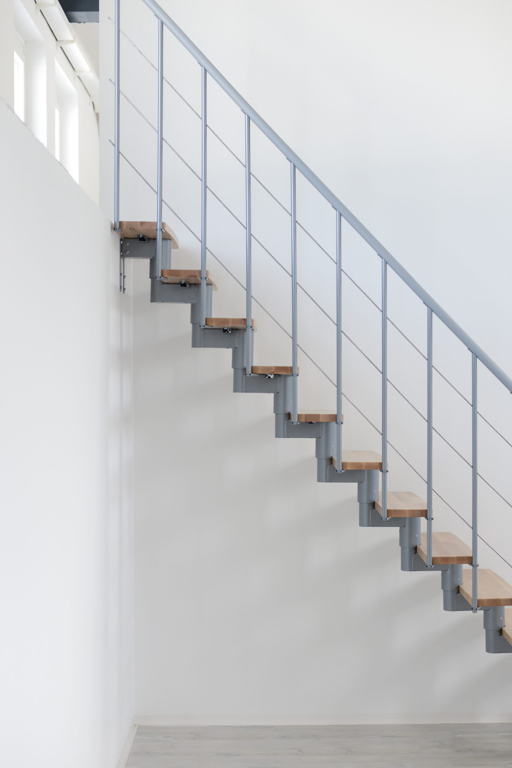 Detailaufnahme der Comfort Top Treppe mit grauer Metallkonstruktion und Buchenholzstufen. Die seitliche Profilansicht zeigt die moderne, schwebende Optik der Stufen sowie die minimalistische Verbindung zwischen Metallstruktur und Holz.