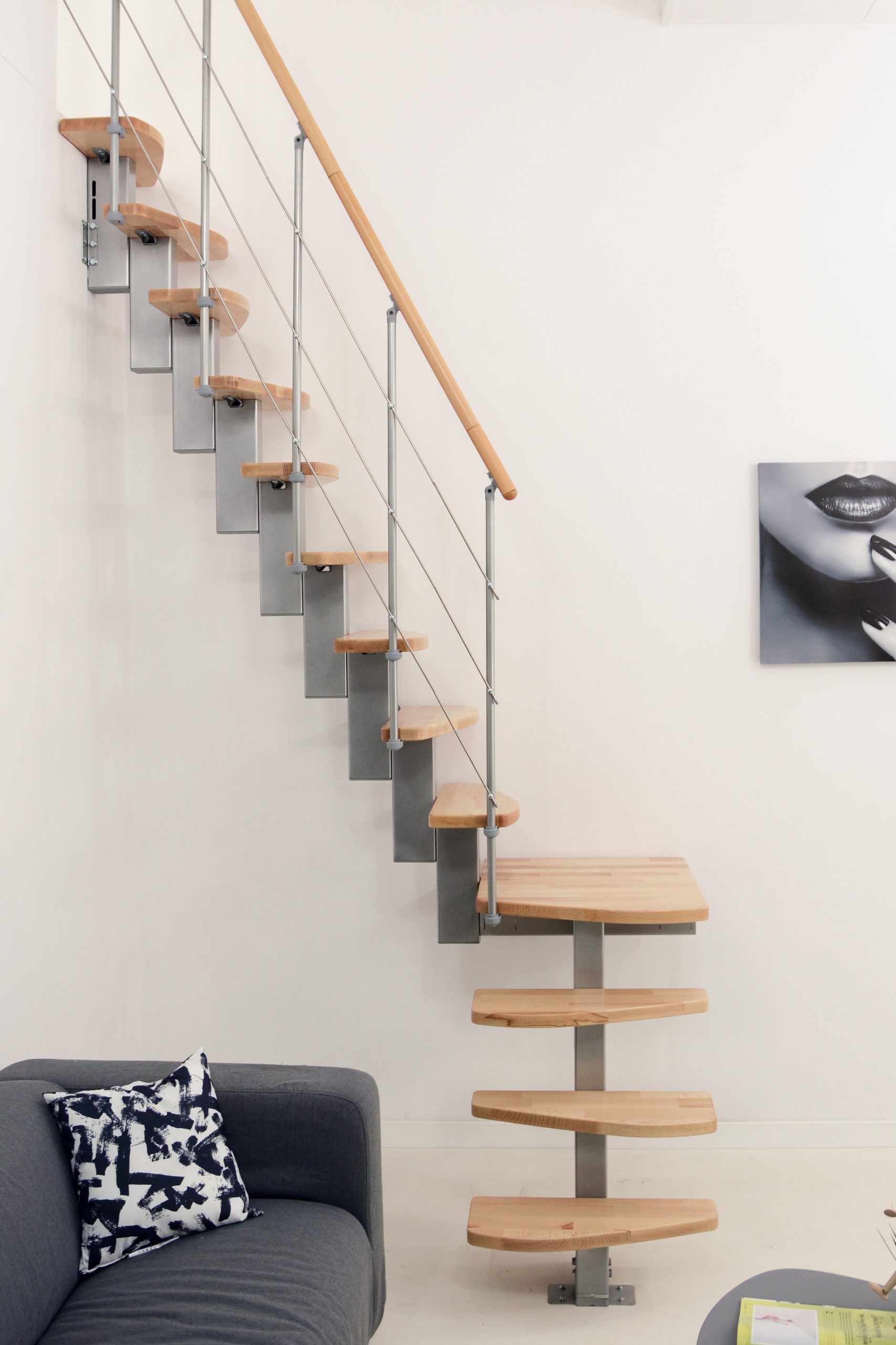 Mittelholmtreppe Quatro Turn mit 1/4 gewendelten Buchenstufen, grauem Metallgeländer mit Untergurten und Holzhandlauf.