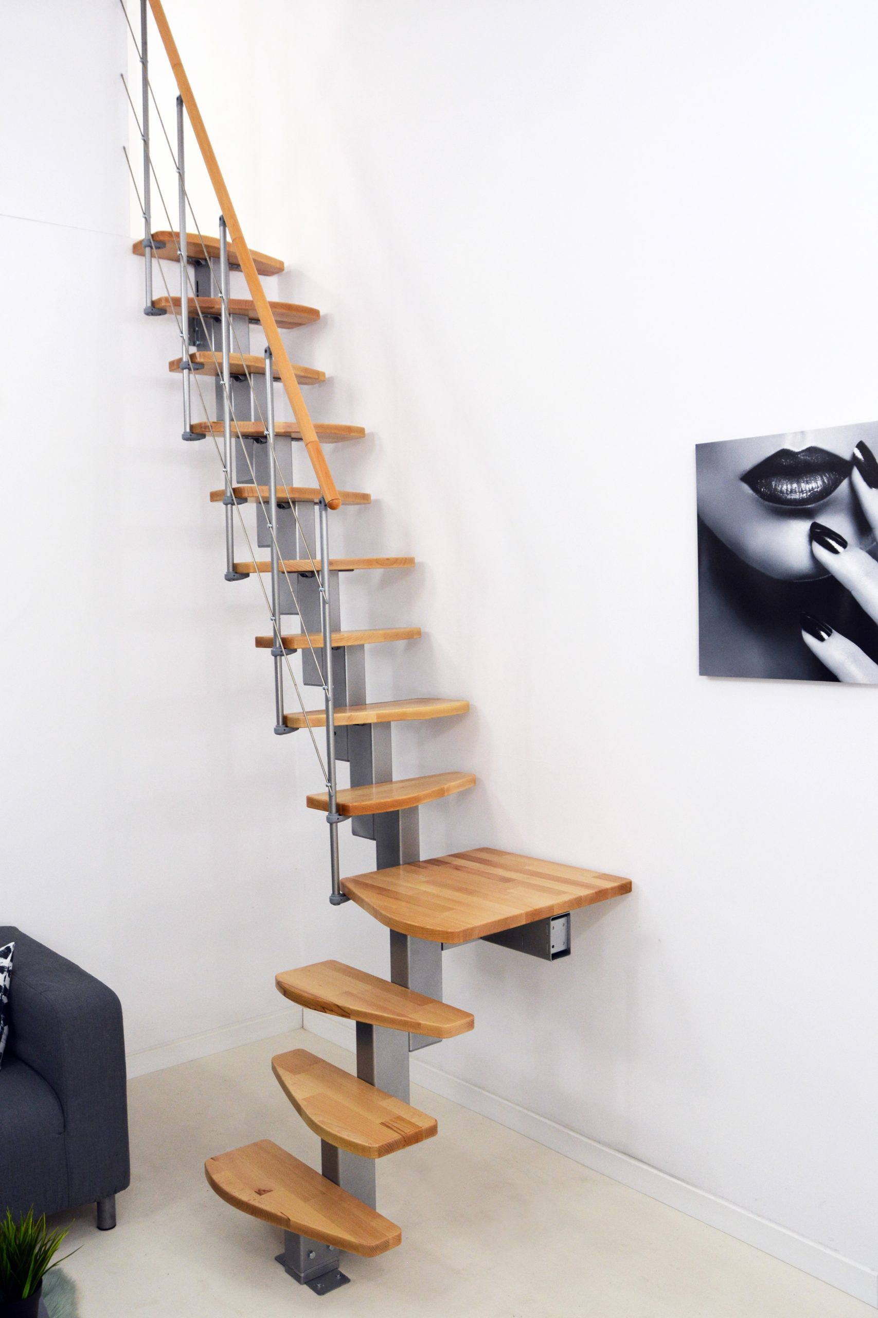 Mittelholmtreppe Quatro Turn mit 1/4 gewendelten Buchenstufen, grauem Metallgeländer mit Untergurten und Holzhandlauf.