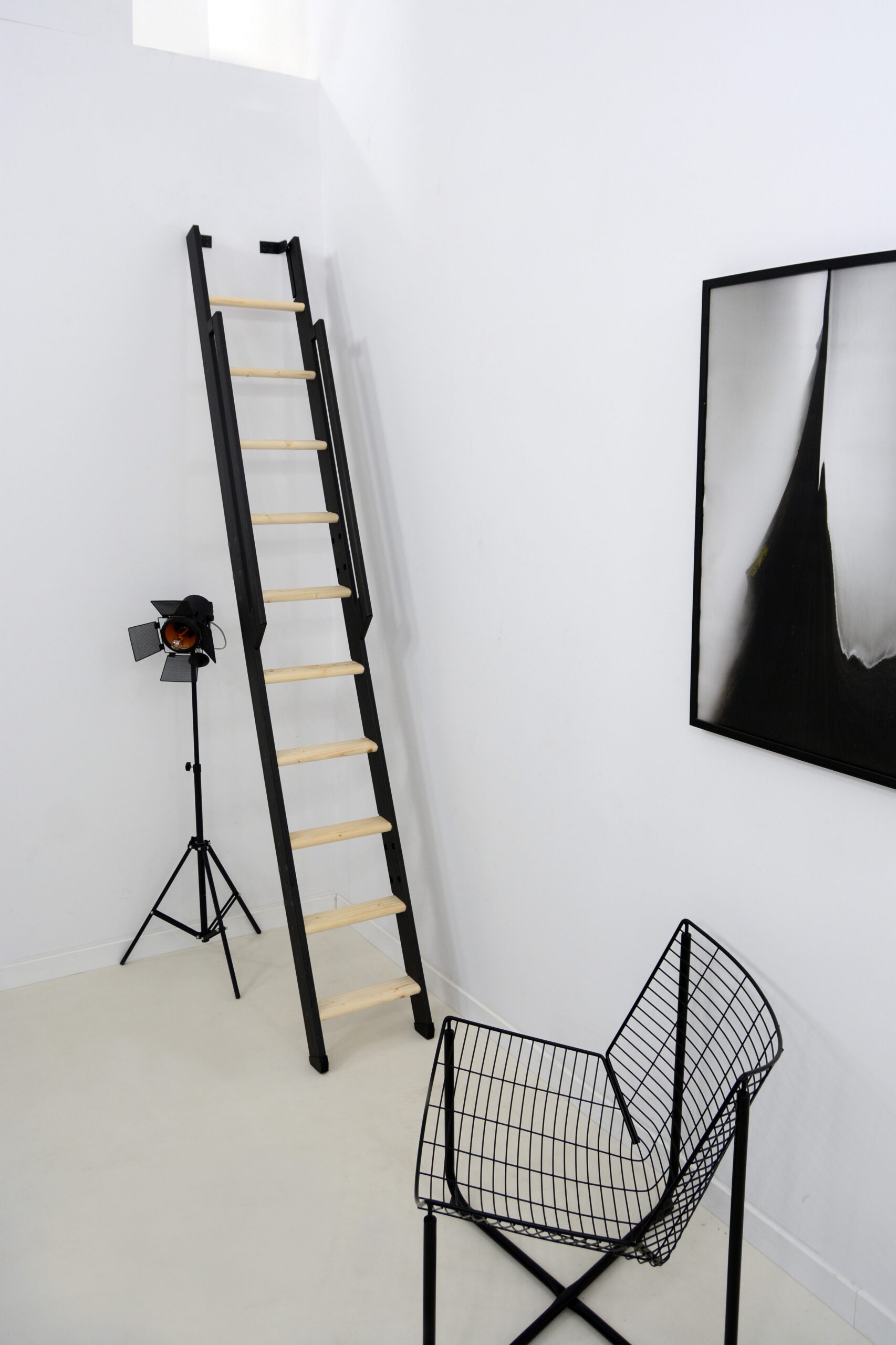 Raumspartreppe Strong mit schwarzem Metallgestell und Trittstufen aus Fichte. Die Treppe ist steil an der Wand montiert und verfügt über ein beidseitiges, schwarzes Metallgeländer.