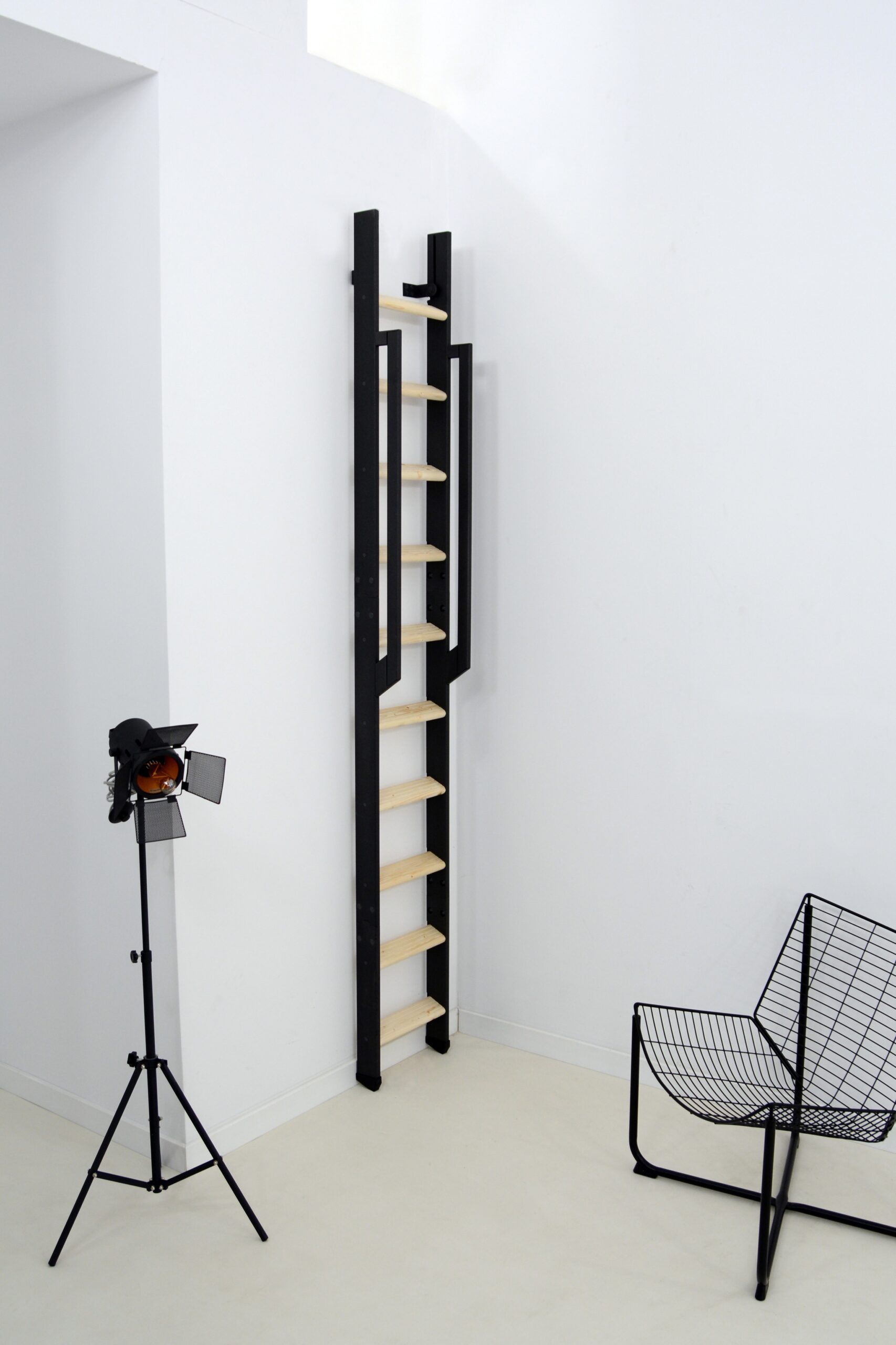 Raumspartreppe Strong aus Fichte mit schwarzem Metallgestell, senkrecht und platzsparend an der Wand eingeklappt.